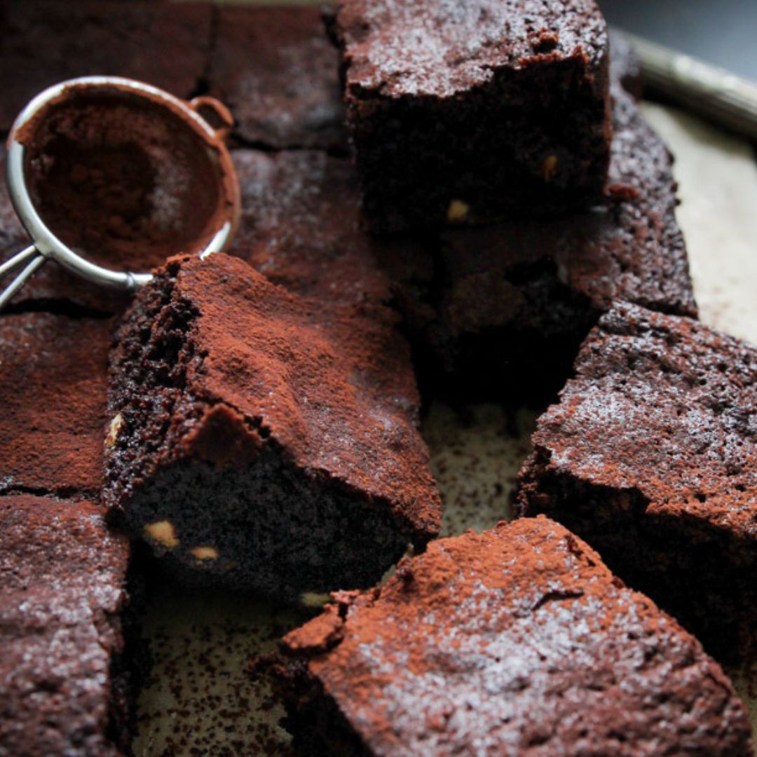 Close up of Secret Kiwi Kitchen brownies cut into suwares and dusted with cocoa powder