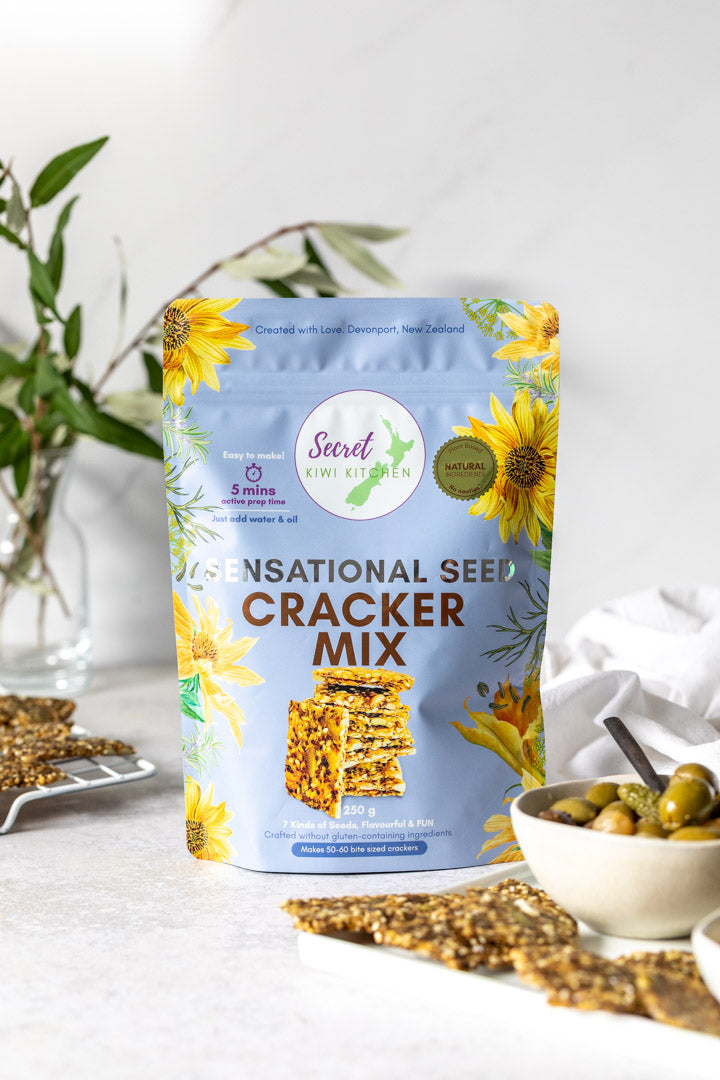 Secret Kiwi Kithcen Sensational Seed Cracker Mix packaging with crackers and bowl on a white surface