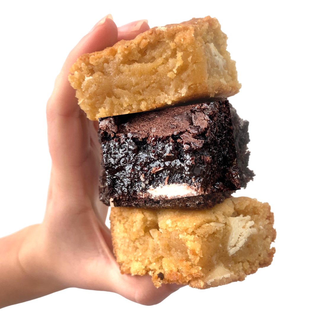 A hand holding a brownie with a oozing chocolate center and two stacked blondies